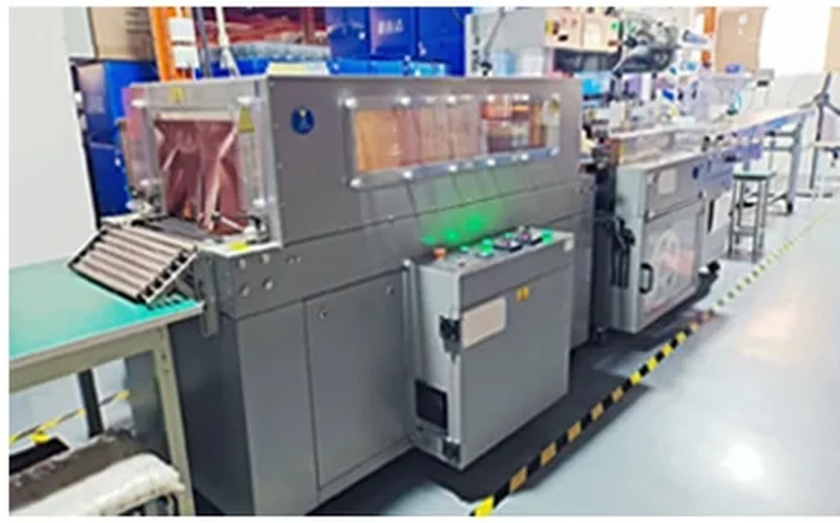 Automatic shrink-wrap and packing line feeding the carton sealer.