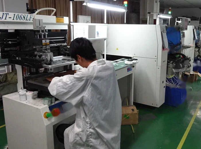 A worker in a cleanroom suit operates a large piece of industrial machinery inside a factory