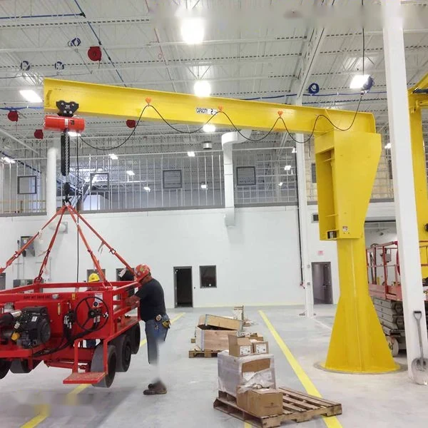 Worker in hard hat operates red machine under yellow gantry crane in warehouse