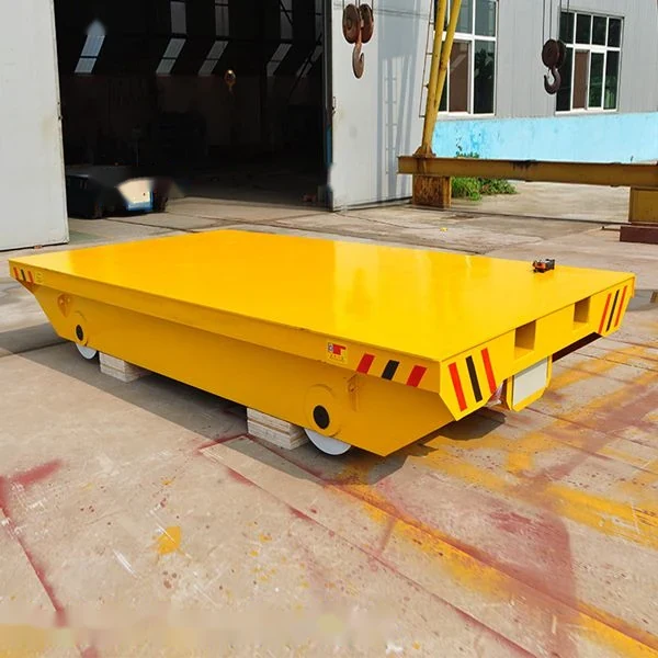 Yellow industrial flatbed transfer cart with wheels sitting on concrete outdoors