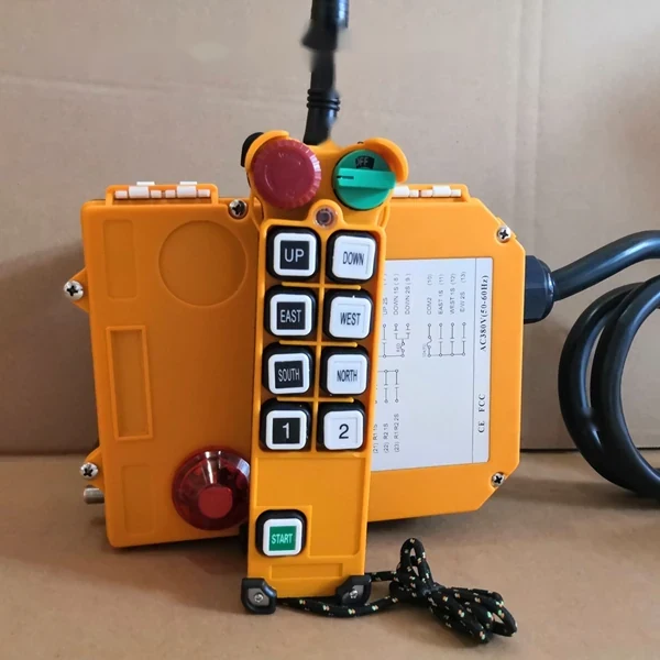 Orange industrial crane radio remote control system: handheld transmitter with direction buttons and receiver unit with cable