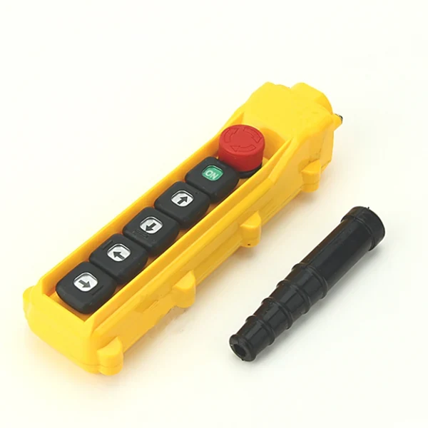 Yellow pendant control station with arrow buttons, green button, red emergency stop, and black cable gland