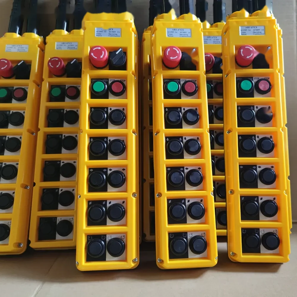 Multiple yellow industrial pendant control stations with red emergency stop buttons and black switches