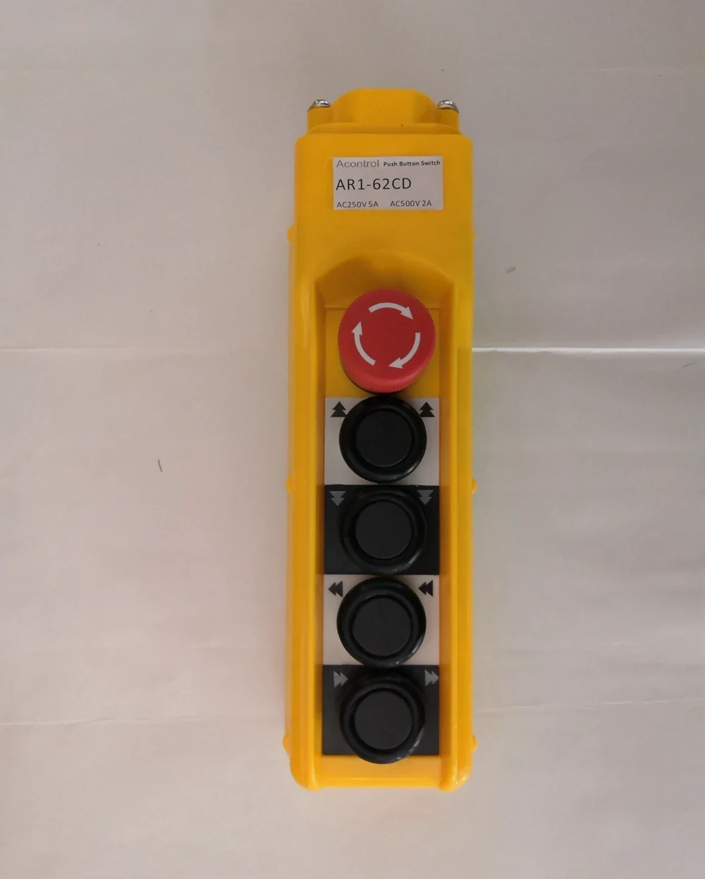 Yellow industrial control pendant with a red emergency stop button and four black push buttons