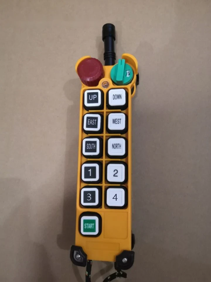 Yellow industrial pendant control station with directional buttons and emergency stop