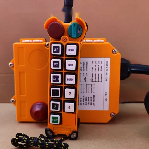 Orange industrial remote control with buttons and receiver unit on cardboard background