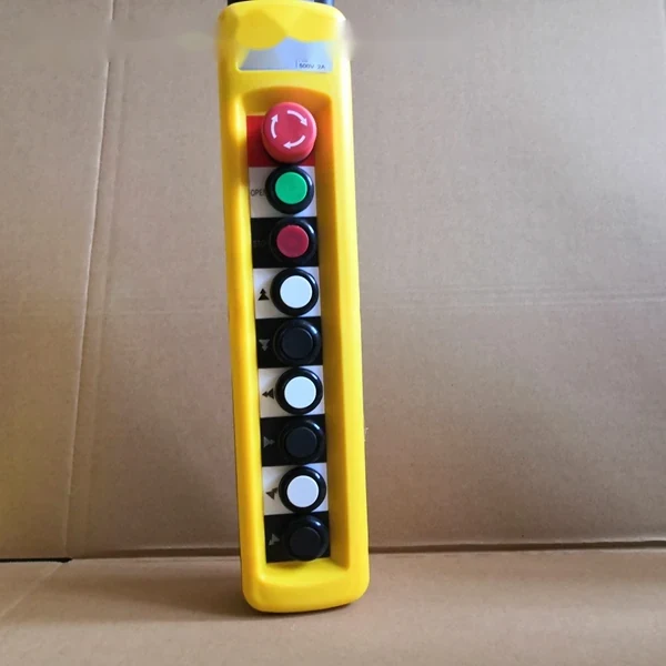 Yellow industrial pendant control station with red emergency stop button and column of black, white, and green push buttons
