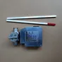 Industrial limit switch with a metal housing and two flat rods, one with a red tip, laid on a brown surface