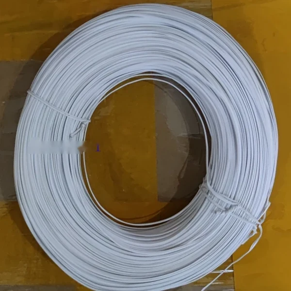Coil of white insulated cable tied with a fastener, lying on a yellowish cardboard surface