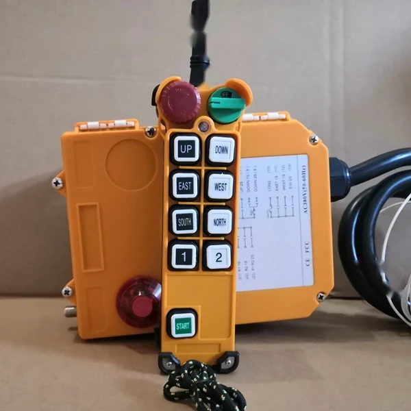 Orange industrial pendant control station with buttons for up, down, east, west, south, and north