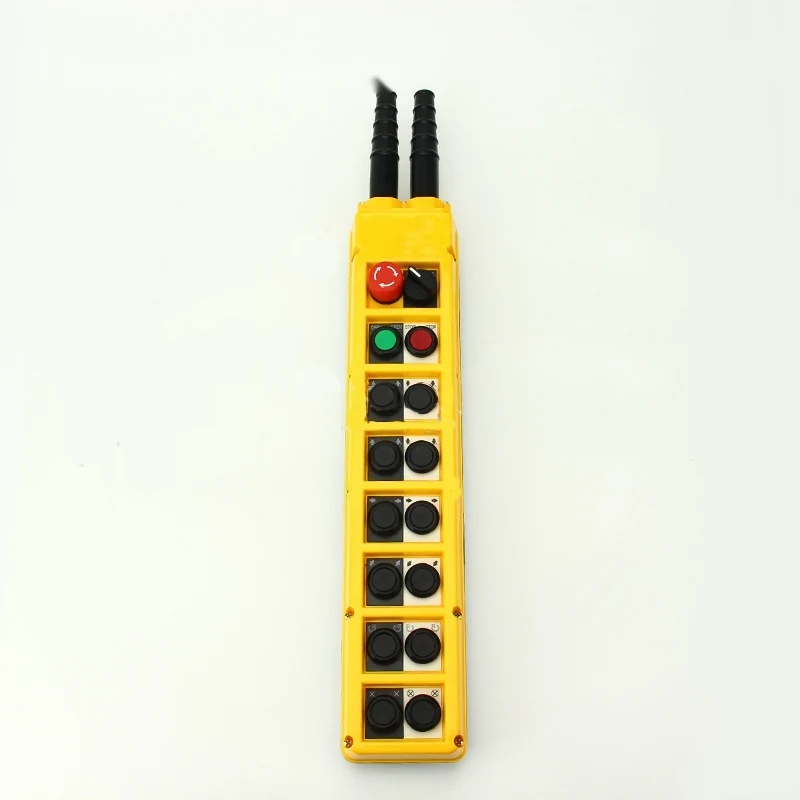Yellow industrial pendant control station with red emergency stop, green and black push buttons, and two cable glands