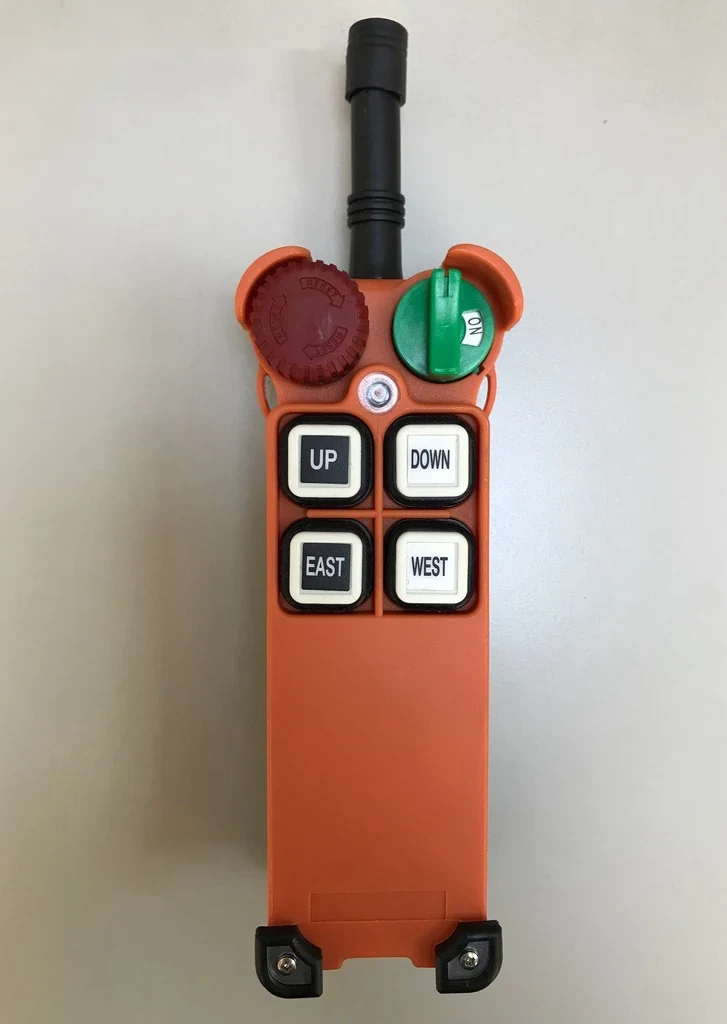 Orange industrial radio remote control transmitter with UP, DOWN, EAST, WEST buttons, rotary switches and antenna