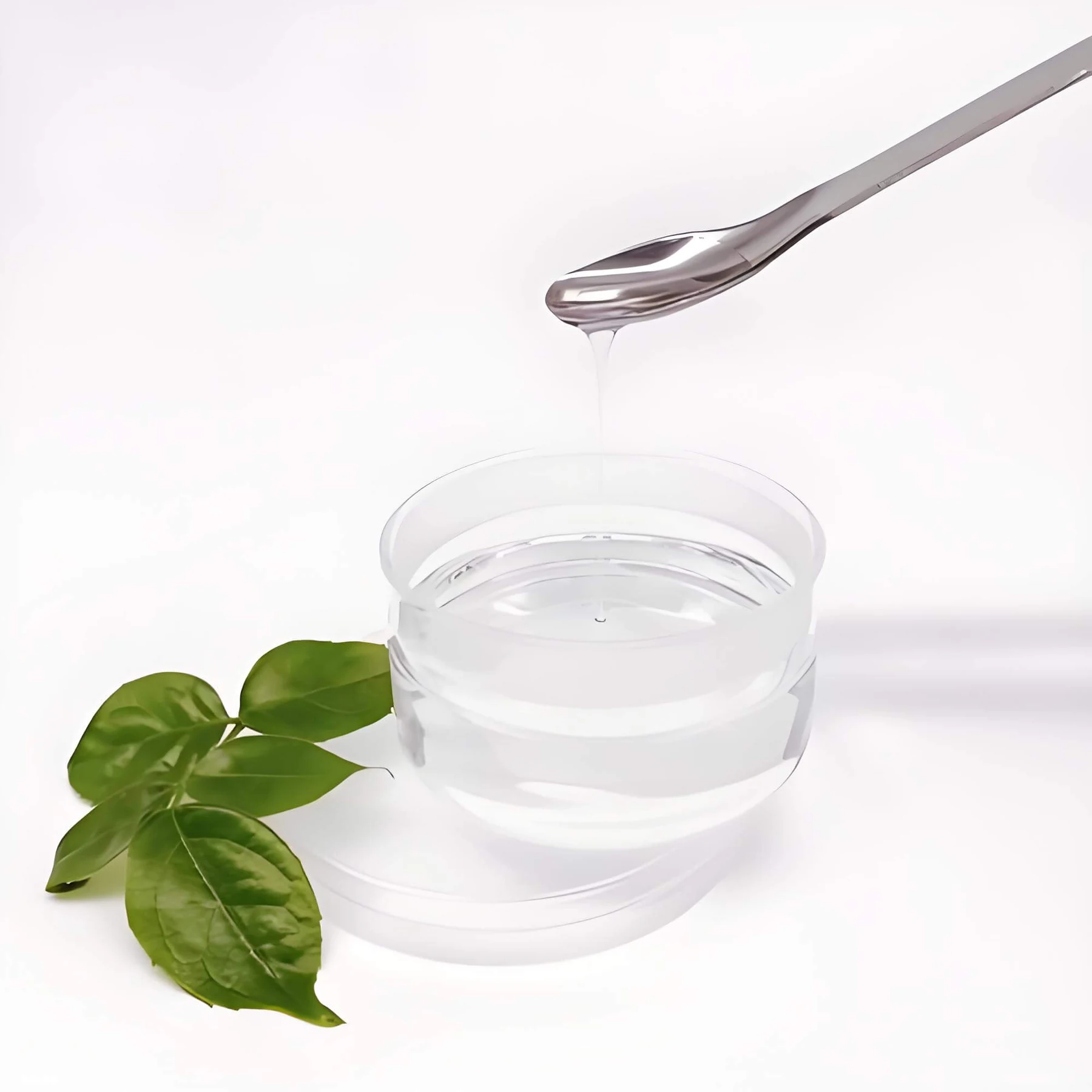 Cosmetic grade glycerin poured from a steel spoon into a glass dish
