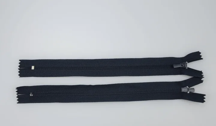 Two black zippers with metal sliders laid horizontally on a white background.