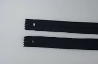 Two navy closed-end zippers with sliders lying parallel on a light grey surface