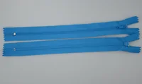 Two blue closed-end zippers with sliders lying parallel on a plain gray background