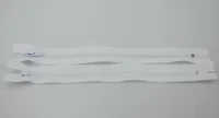 White zipper with slider lying in a wavy line on a plain light gray background