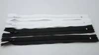 Several white and black zippers with sliders laid flat on a white surface