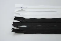 White and black zippers with sliders laid diagonally on a plain white surface