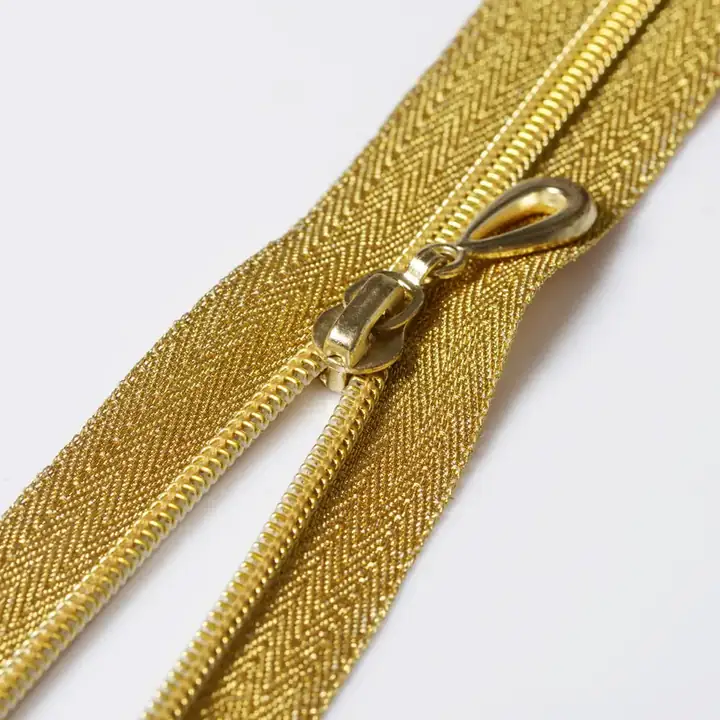 Golden metal zipper with brass teeth and slider pull lying open on a clean white background