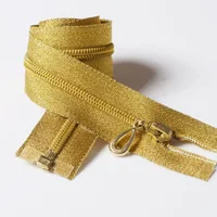 Coiled golden zipper with metal slider and pull tab laid out on a white background