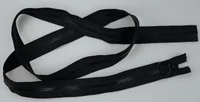 Coiled black zippers with pull tabs laid loosely on a plain light gray background