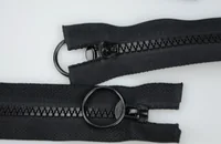 Two black zippers with large round O-ring pullers laid on a white background
