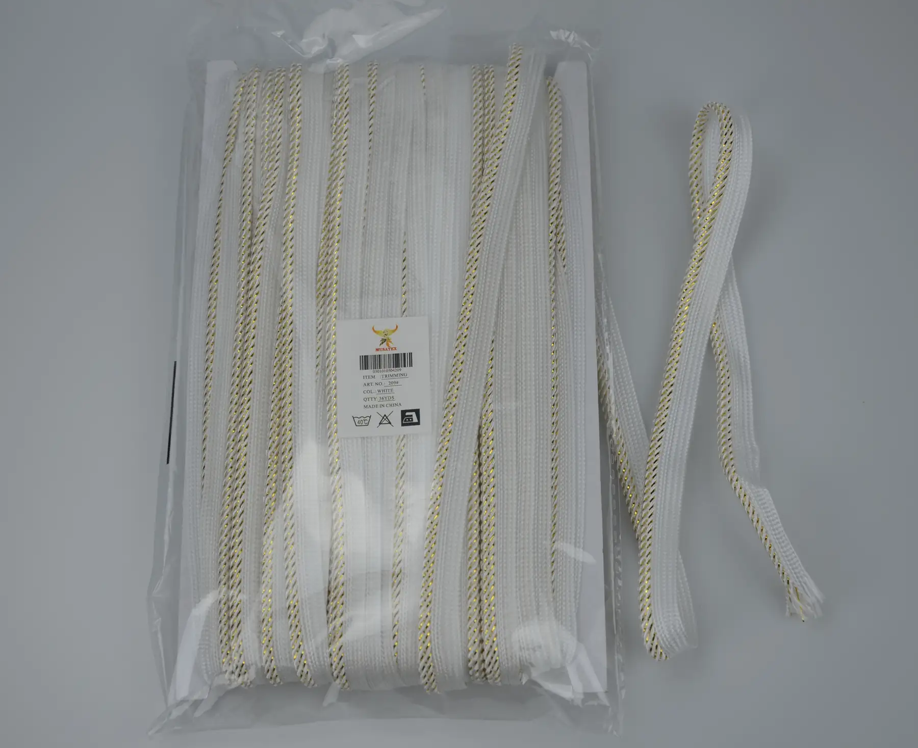Packaged white and gold braided trim with MUSATEX product label and barcode on a white background