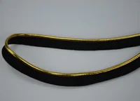 Coiled black woven trim with a metallic gold stripe along its edge on a plain background