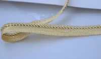 Woven metallic trim ribbon in gold tones laid on a plain white surface