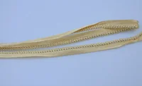Golden braided trim ribbon laid loosely on a plain light blue background