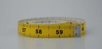 Coiled yellow tailor's measuring tape with visible markings around 57-59 centimeters on a white background