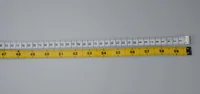 Two measuring tapes laid horizontally on a grey background, one white with black markings and one yellow with visible numbers