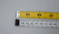 Yellow measuring tape showing 56-59 cm and white tape with centimeter markings lying on a gray surface