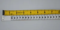 Yellow inch measuring tape and white metric fiberglass tape with numbered markings laid on a plain surface