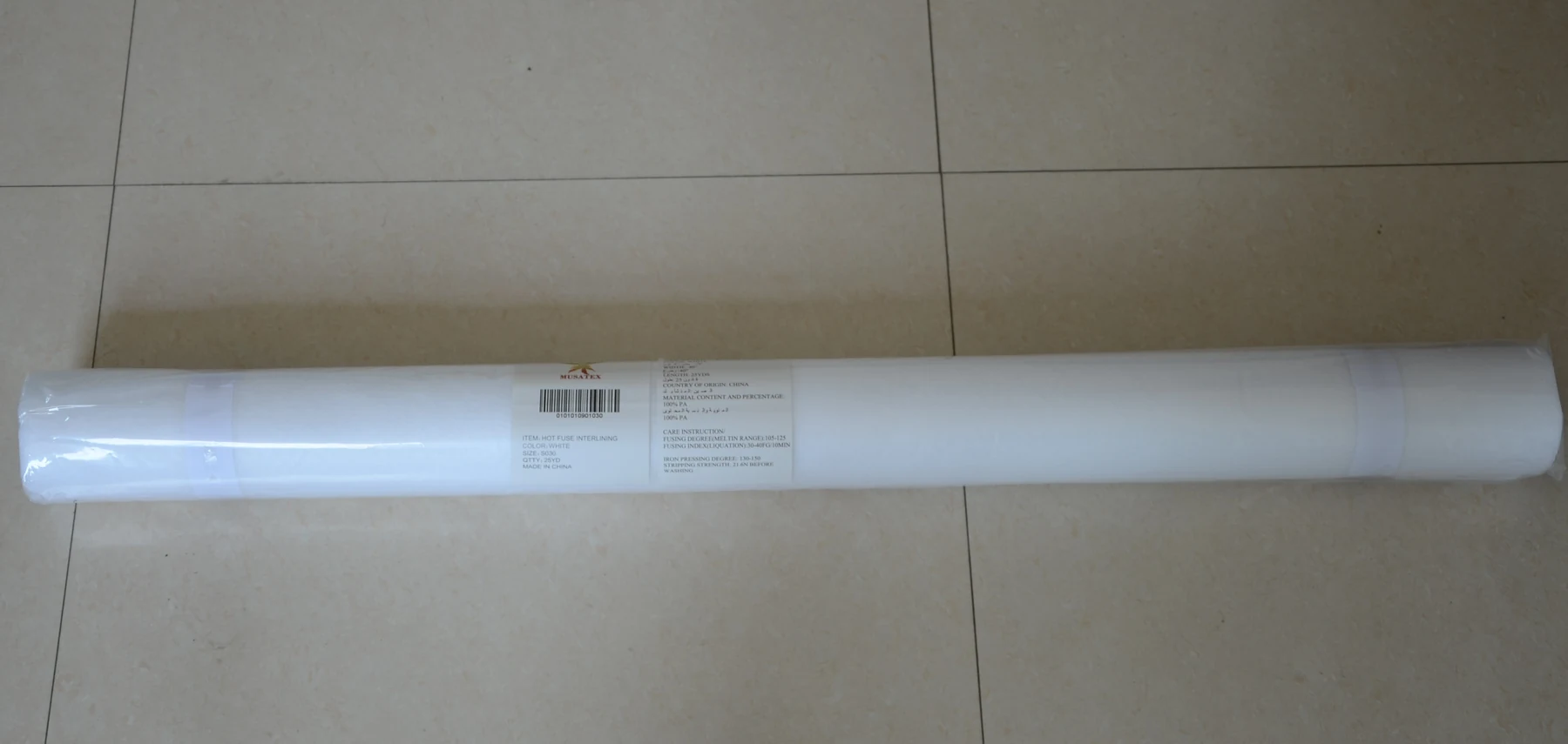A long roll of white fabric packaging lying horizontally on a tiled floor.