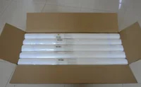 Open cardboard box containing five white rolled products with small labels, on a tiled floor