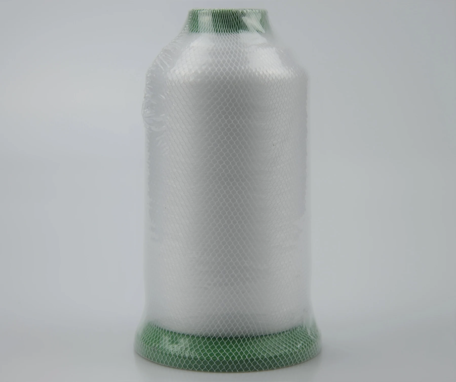 Large cone of white industrial thread wrapped in protective mesh, with green plastic ends, on a plain light background