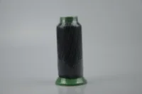 Black thread spool with green plastic ends on a plain light gray background
