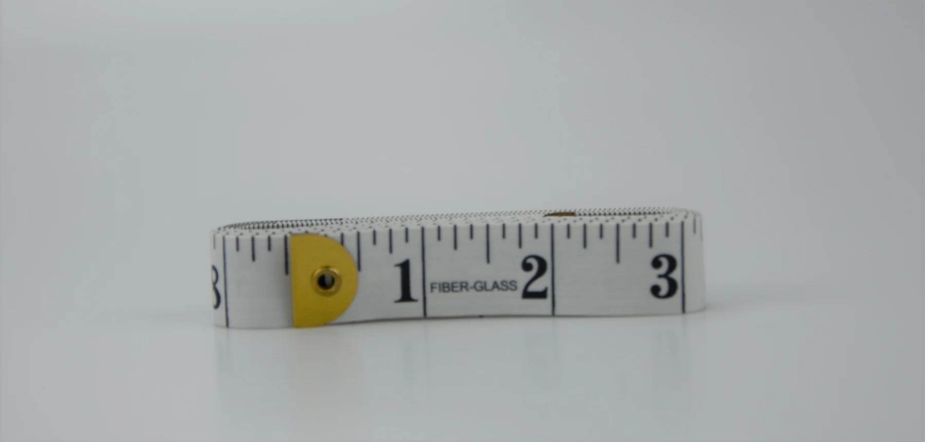 Fiberglass measuring tape coiled on a plain white background with yellow end tab