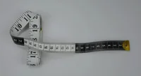 Curled measuring tape with black and white dual-sided markings on a plain light background