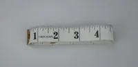 White fiberglass measuring tape showing inch markings 1 through 4 on a plain light background