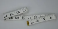 White flexible measuring tape with black markings coiled on a light surface
