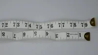 White tailor measuring tapes showing inch markings 72–79 coiled on a plain light background