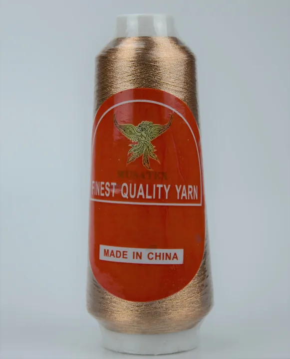 Copper metallic yarn cone with orange MUSATEX label reading FINEST QUALITY YARN and MADE IN CHINA