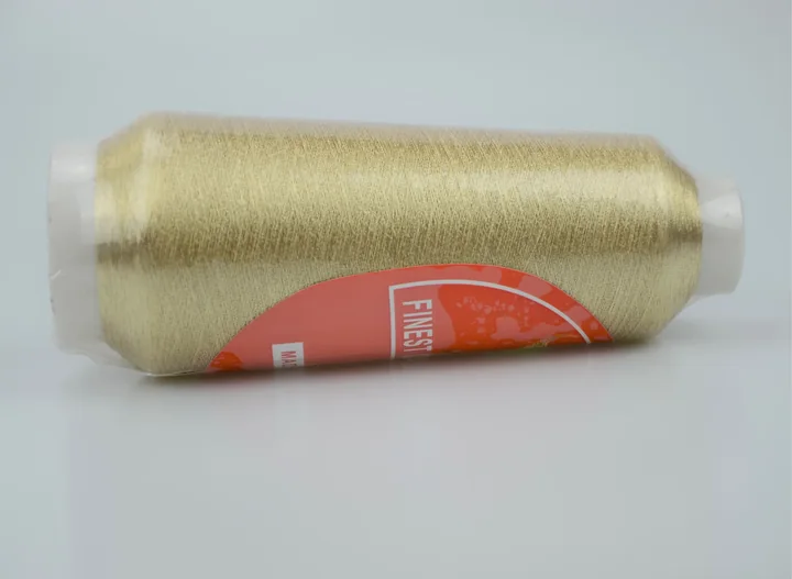 A gold thread cone with a red label resting on a white background.