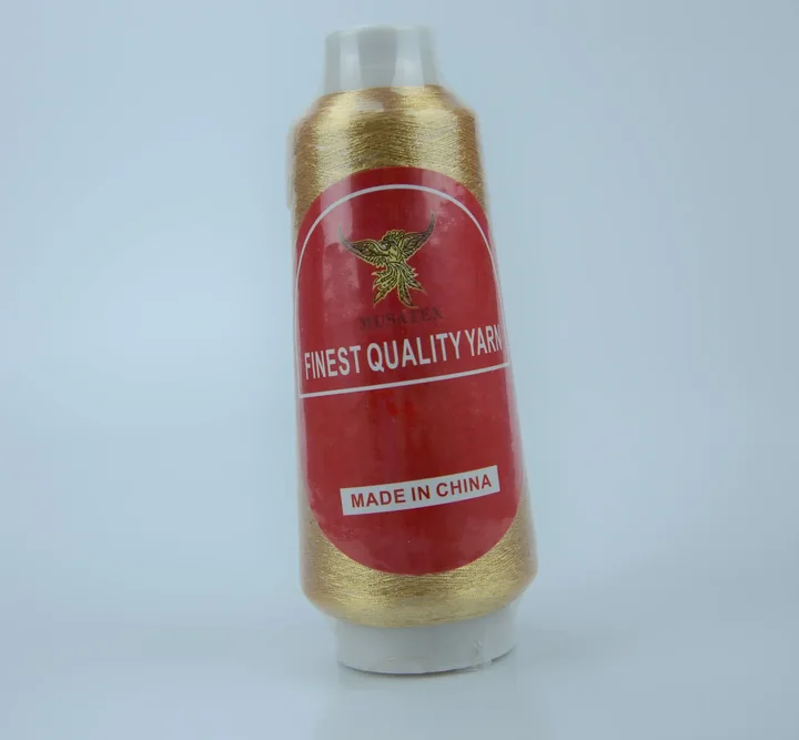 A gold thread cone with a red MUSATEX label on a white background.