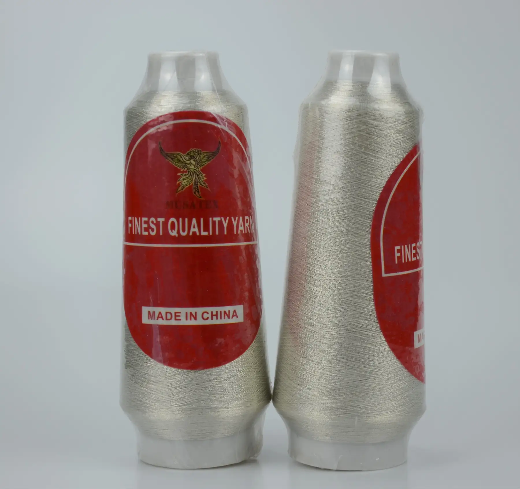 Two cones of silver metallic thread with red MUSATEX labels.