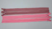 Four pink and mauve closed-end zippers with pull sliders arranged horizontally on a plain light background.