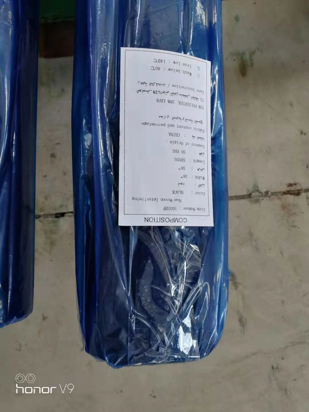 Rolled black fabric in plastic packaging with a composition label.
